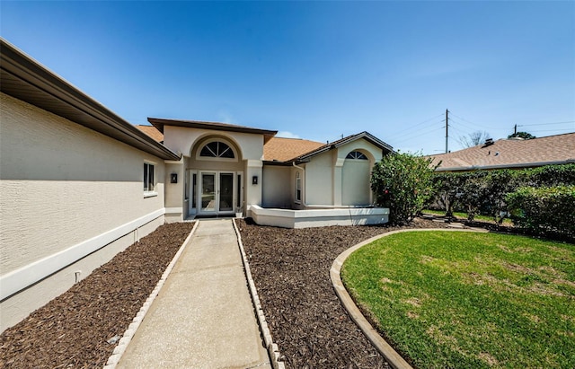 view of front of house featuring a front lawn, french doors, and stucco siding