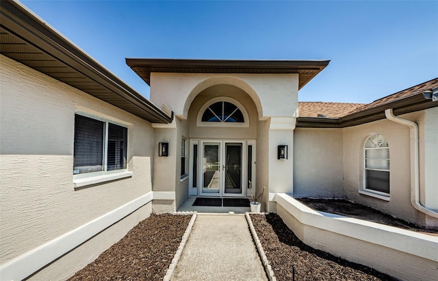 doorway to property with stucco siding and a shingled roof