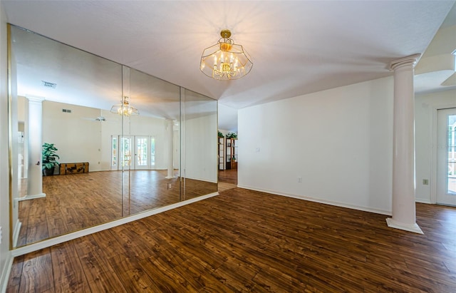 unfurnished room with wood-type flooring, an inviting chandelier, and decorative columns