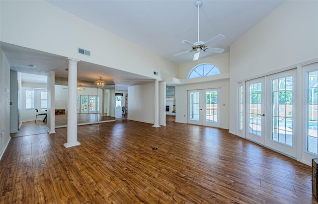 unfurnished living room featuring visible vents, high vaulted ceiling, dark wood finished floors, french doors, and decorative columns