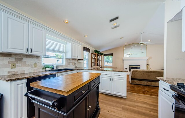 kitchen featuring a sink, plenty of natural light, butcher block countertops, and white cabinets