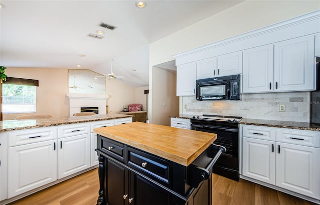 kitchen featuring visible vents, black appliances, open floor plan, white cabinetry, and lofted ceiling