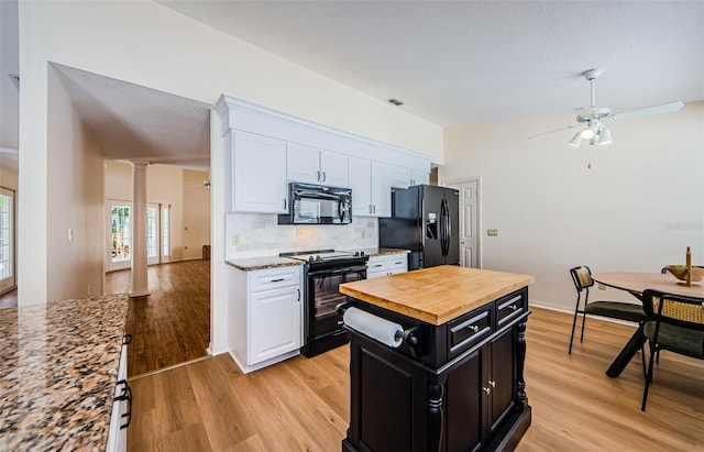 kitchen featuring dark cabinetry, black appliances, white cabinetry, and butcher block counters