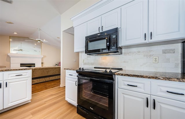 kitchen with a fireplace, black appliances, dark stone counters, and vaulted ceiling