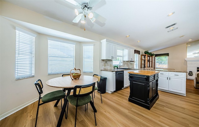 kitchen featuring butcher block countertops, a sink, black dishwasher, light wood-type flooring, and a center island