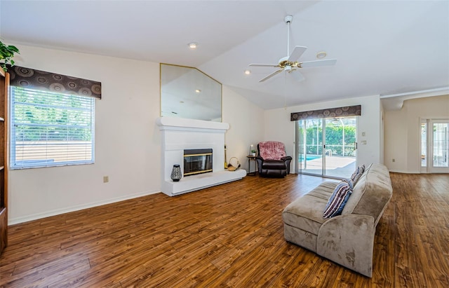 unfurnished living room featuring wood finished floors, baseboards, a ceiling fan, vaulted ceiling, and a glass covered fireplace