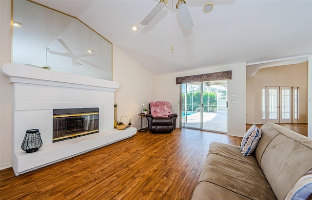 living room featuring a ceiling fan, baseboards, lofted ceiling, hardwood / wood-style flooring, and a glass covered fireplace