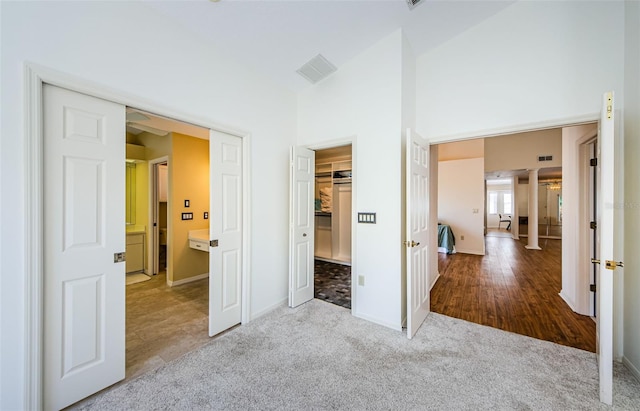 unfurnished bedroom featuring carpet, visible vents, baseboards, a high ceiling, and a closet