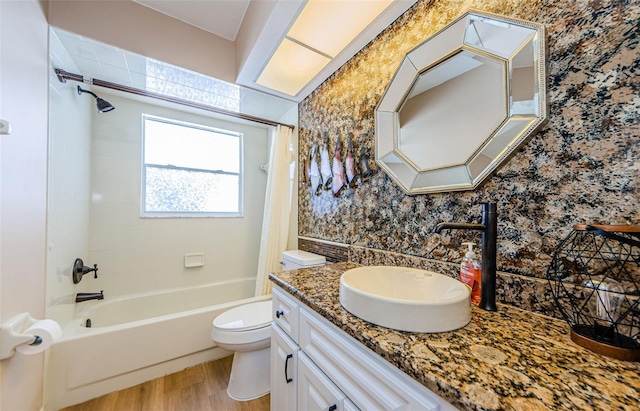 bathroom with toilet, shower / bath combination with curtain, wood finished floors, wallpapered walls, and vanity