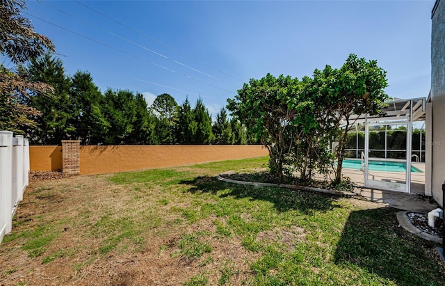 view of yard with glass enclosure, a fenced backyard, and a fenced in pool