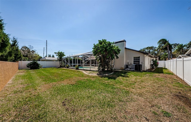 view of yard featuring glass enclosure, a fenced backyard, and a fenced in pool