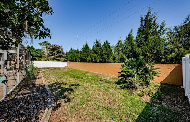 view of yard with glass enclosure and a fenced backyard