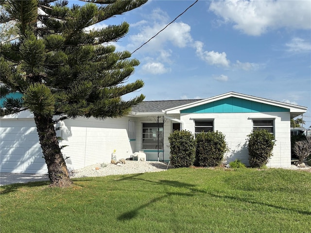 ranch-style home with a shingled roof and a front lawn