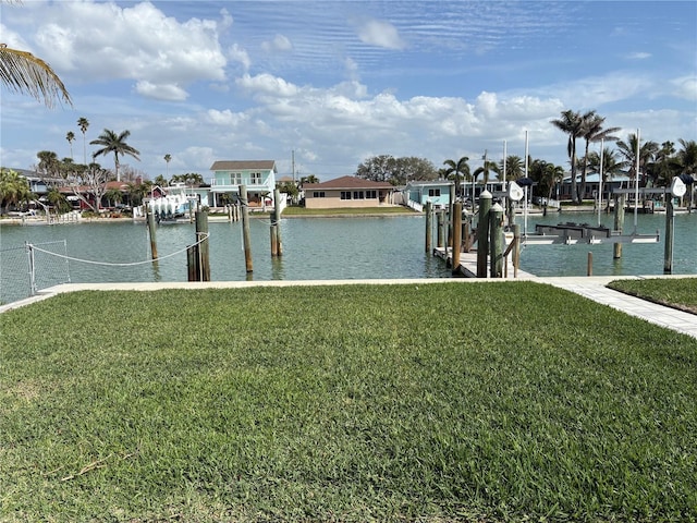 dock area featuring a water view, boat lift, and a yard