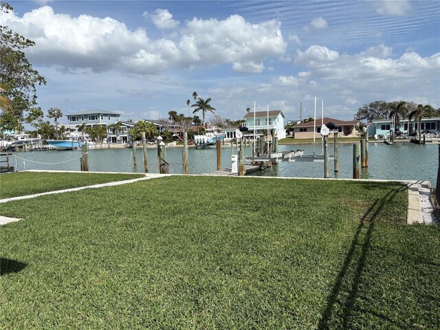 dock area with a water view, boat lift, a residential view, and a yard