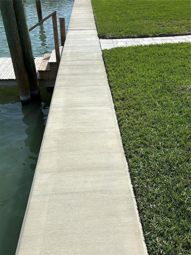 view of dock with a water view and a lawn