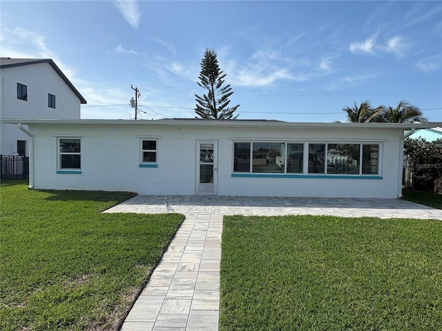 rear view of property featuring concrete block siding, a patio area, and a yard