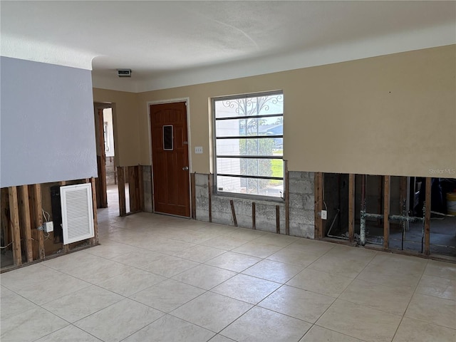 unfurnished living room featuring light tile patterned floors, visible vents, and wainscoting