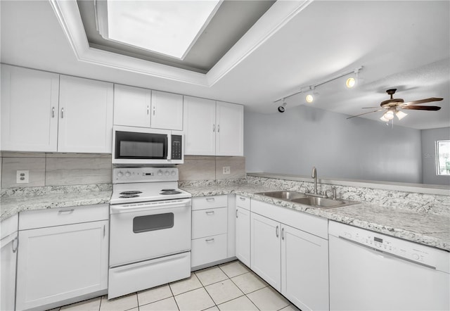 kitchen featuring light tile patterned floors, white appliances, a sink, white cabinetry, and tasteful backsplash