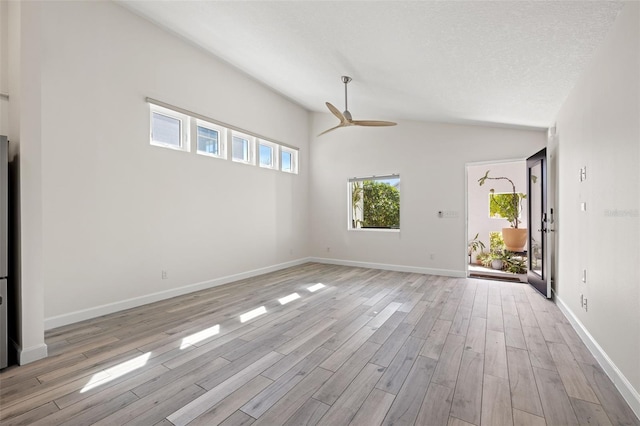 unfurnished living room with light wood-style flooring, a ceiling fan, a textured ceiling, baseboards, and vaulted ceiling