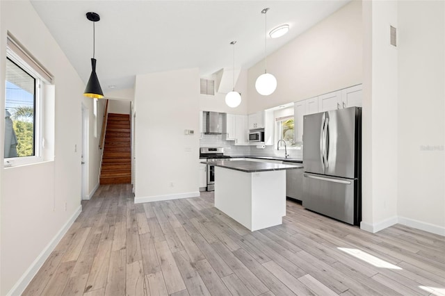 kitchen featuring tasteful backsplash, visible vents, wall chimney range hood, stainless steel appliances, and white cabinetry