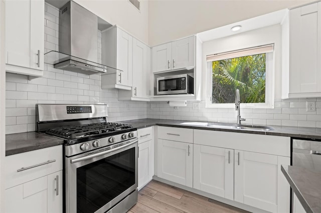 kitchen featuring dark countertops, appliances with stainless steel finishes, and wall chimney range hood