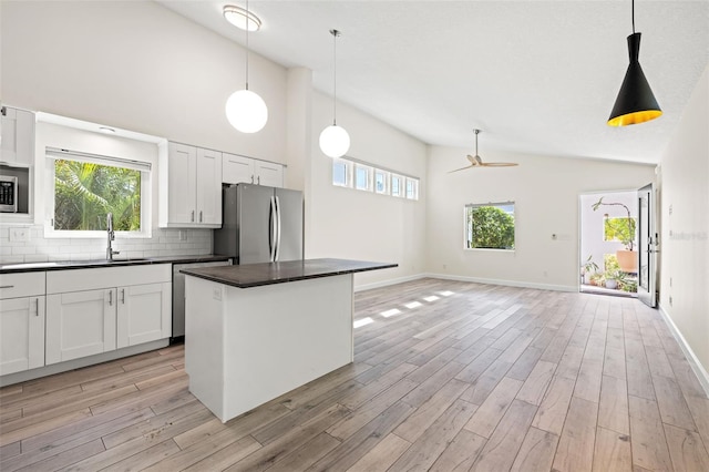 kitchen featuring dark countertops, light wood finished floors, stainless steel appliances, and a sink