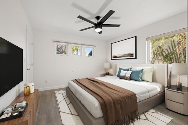 bedroom with ceiling fan, baseboards, and light wood-style flooring