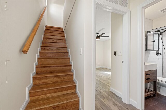 stairway with visible vents, baseboards, ceiling fan, and wood finished floors