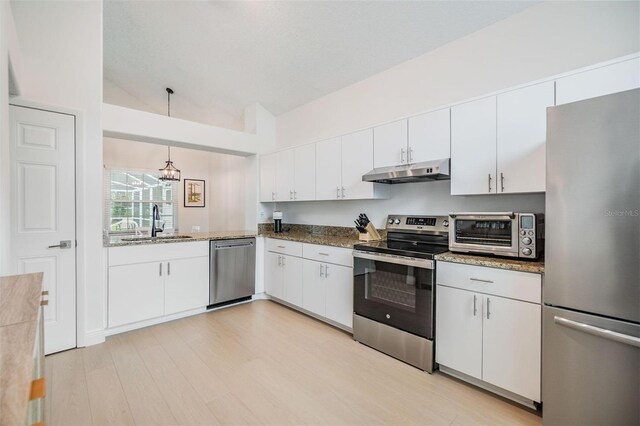 kitchen featuring a toaster, stainless steel appliances, under cabinet range hood, white cabinetry, and a sink