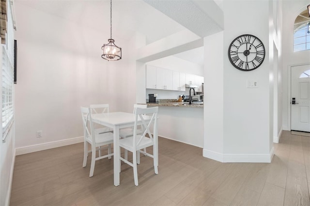 dining area with light wood finished floors, baseboards, and an inviting chandelier