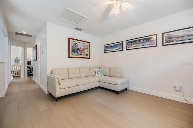 living area featuring attic access, visible vents, light wood-style floors, and baseboards