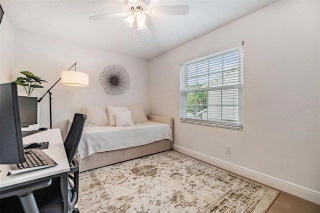 bedroom featuring a ceiling fan, baseboards, and wood finished floors