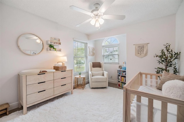 bedroom featuring light carpet, baseboards, and a textured ceiling