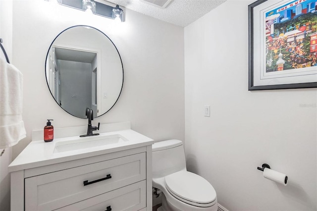 bathroom with a textured ceiling, vanity, and toilet