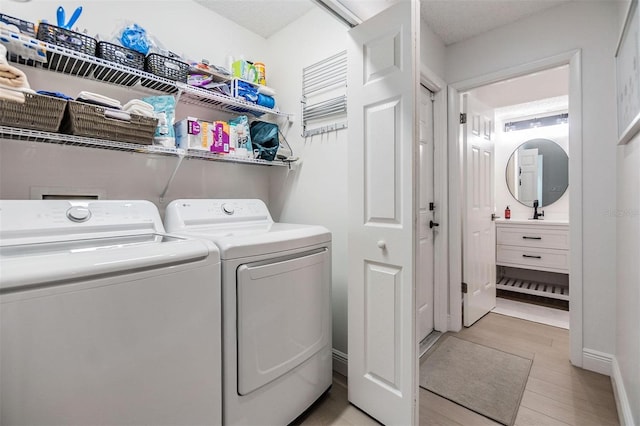 washroom featuring light wood-style flooring, laundry area, washer and clothes dryer, and baseboards