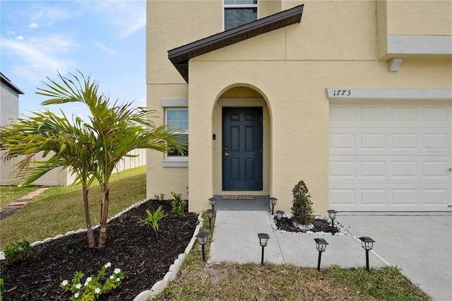 doorway to property with an attached garage and stucco siding