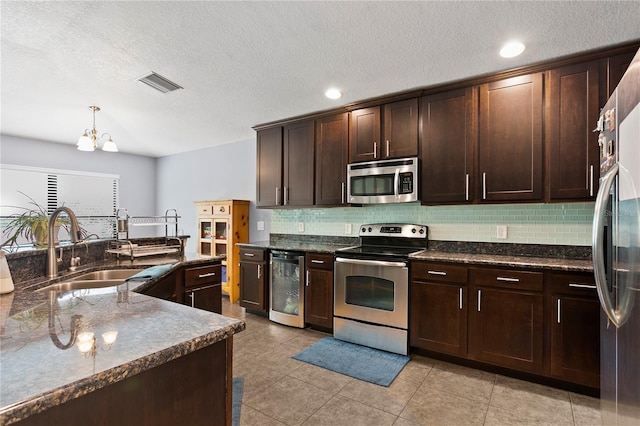 kitchen with wine cooler, a sink, visible vents, appliances with stainless steel finishes, and decorative backsplash