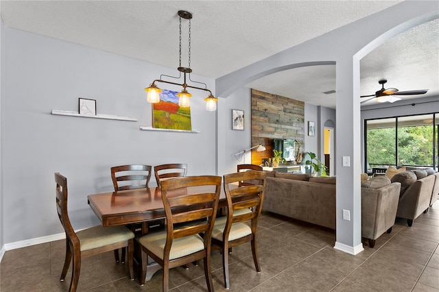 dining room featuring arched walkways, ceiling fan, and a textured ceiling