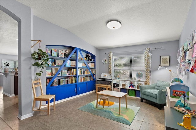 sitting room with arched walkways, a textured ceiling, baseboards, and tile patterned floors