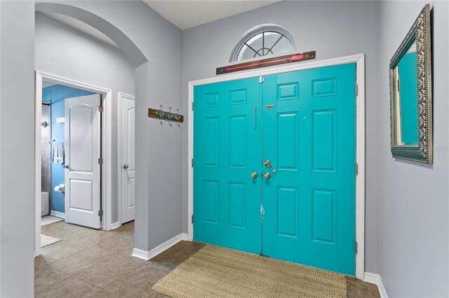 foyer entrance with baseboards and arched walkways