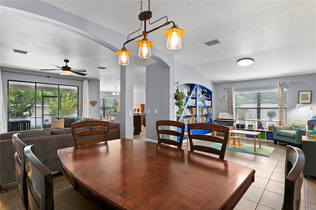 dining room with arched walkways, light tile patterned flooring, visible vents, and a ceiling fan