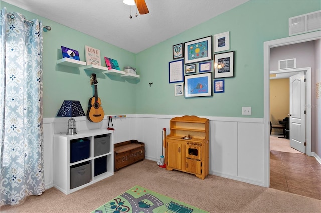 playroom featuring a wainscoted wall, carpet, visible vents, and a ceiling fan