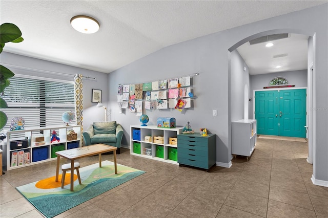 rec room featuring baseboards, visible vents, arched walkways, lofted ceiling, and a textured ceiling