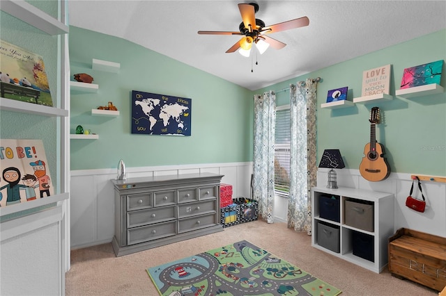 playroom with a ceiling fan, lofted ceiling, wainscoting, and carpet