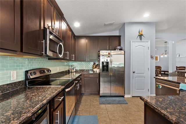 kitchen with arched walkways, light tile patterned floors, dark brown cabinetry, stainless steel appliances, and tasteful backsplash