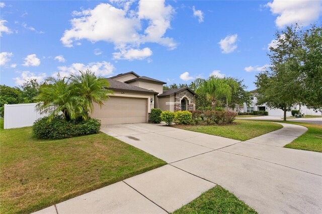 view of front facade with stucco siding, concrete driveway, a front yard, a garage, and stone siding