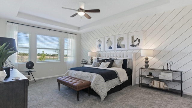 bedroom with ceiling fan, a raised ceiling, carpet flooring, and baseboards