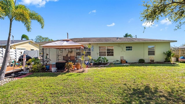 back of property with a lawn, fence, and stucco siding