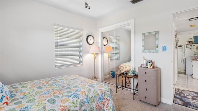 carpeted bedroom featuring freestanding refrigerator, a closet, and visible vents